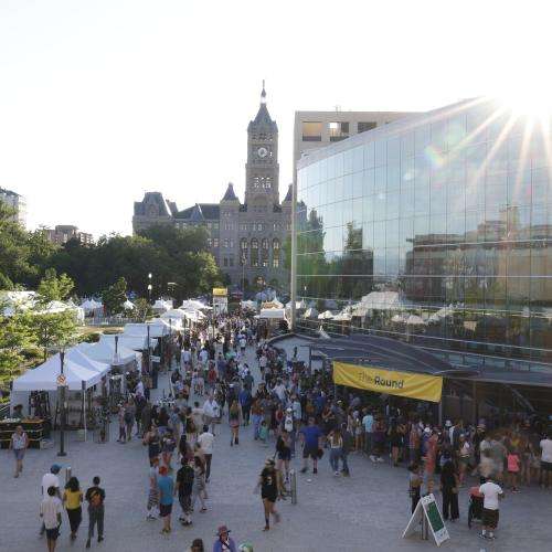 aerial view of festival with people and tents and city hall in the center
