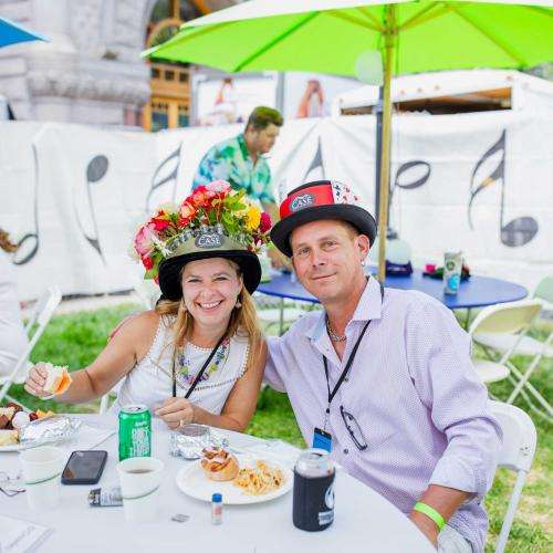 people sitting with fun hats at tables outside with colorful umbrellas people sitting with fun hats at tables outside with colorful umbrellas