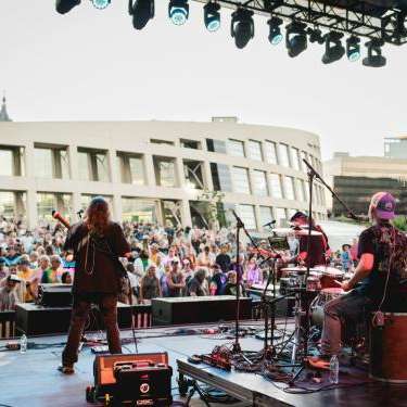 Blonde woman playing guitar with band members in the background