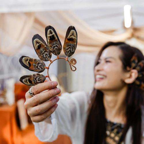 artist holding her feather art and smiling