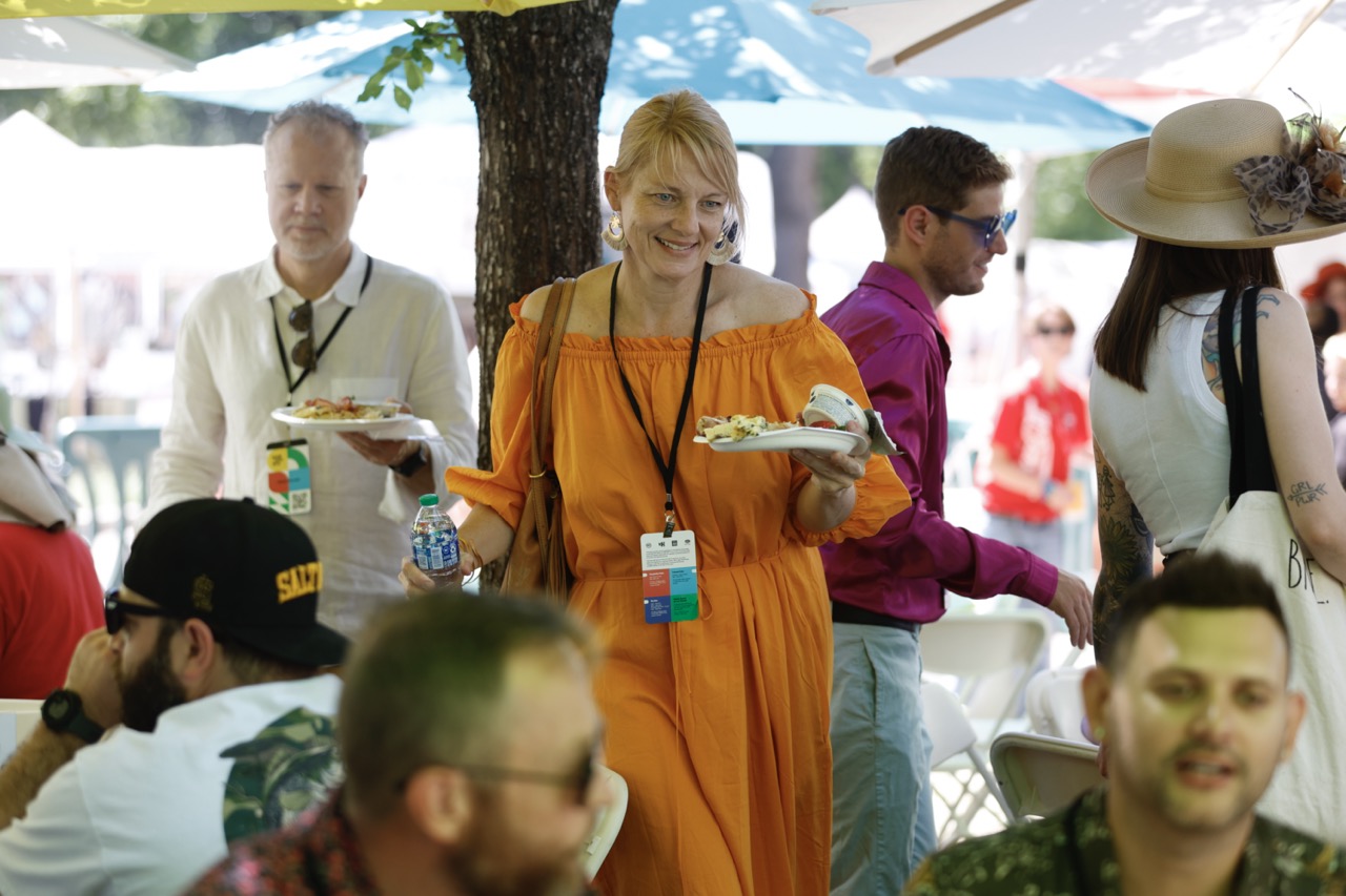 woman in orange dress holding plates of food