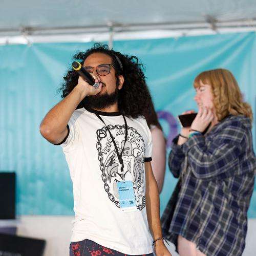 man with dark curly hair with microphone